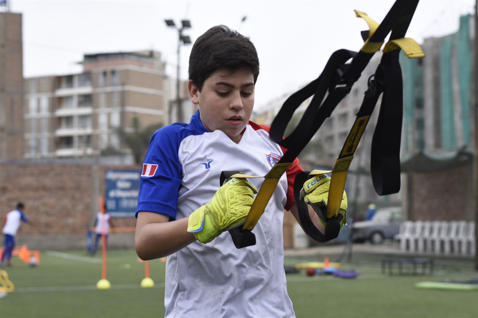 Alumno entrenando fuerza con cinta TRX en la cancha