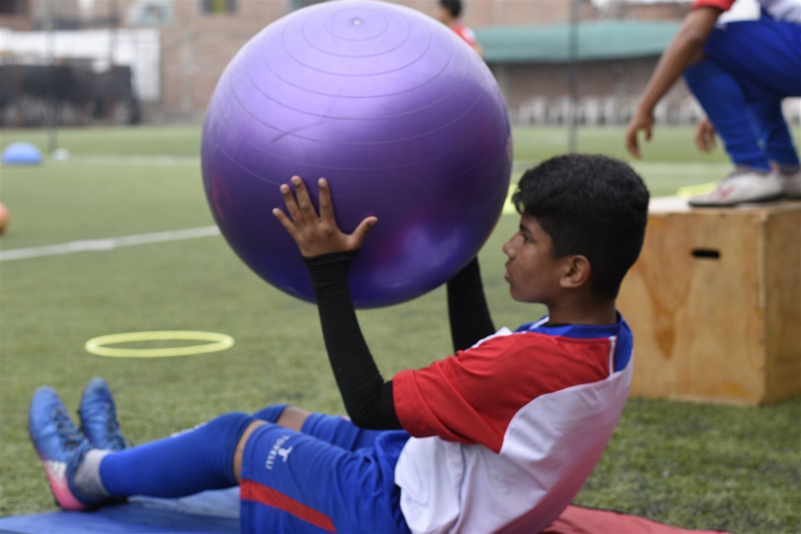Alumno trabajando equilibrio y fuerza con una pelota grande