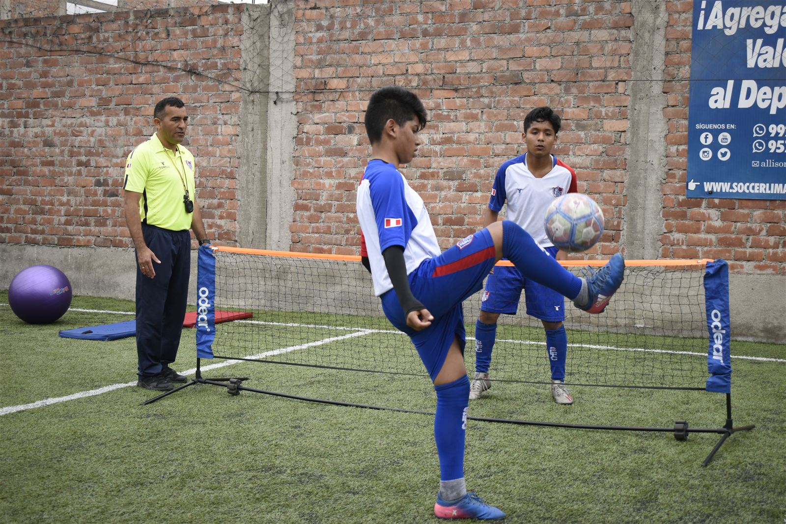 Alumnos practicando control y golpeo de balón sobre la red