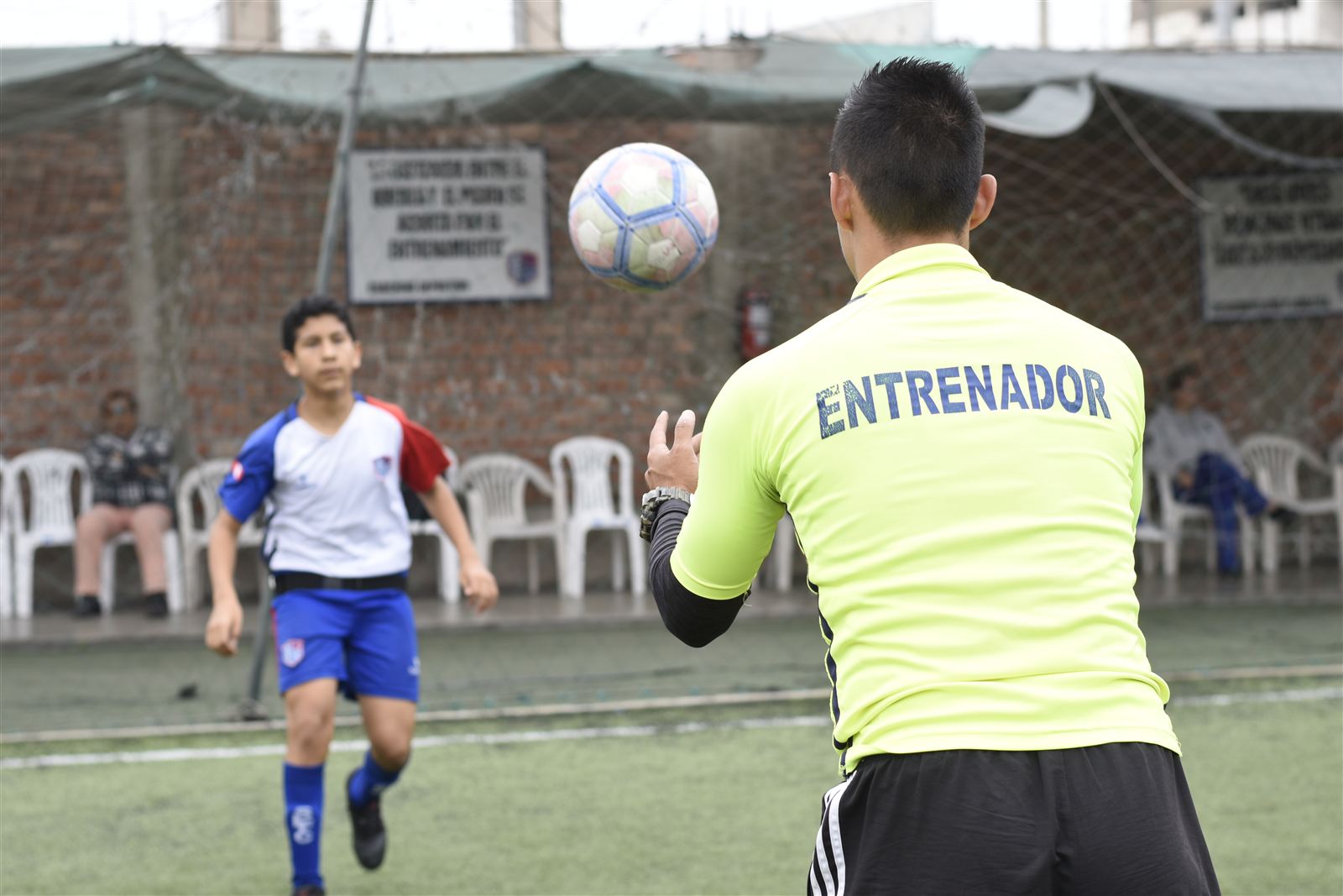 Entrenador pasando el balón a un alumno durante el entrenamiento