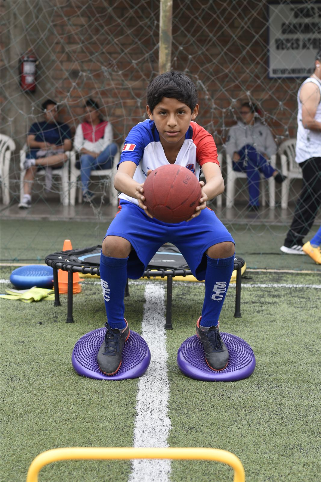 Alumno con balón medicinal sobre discos de equilibrio