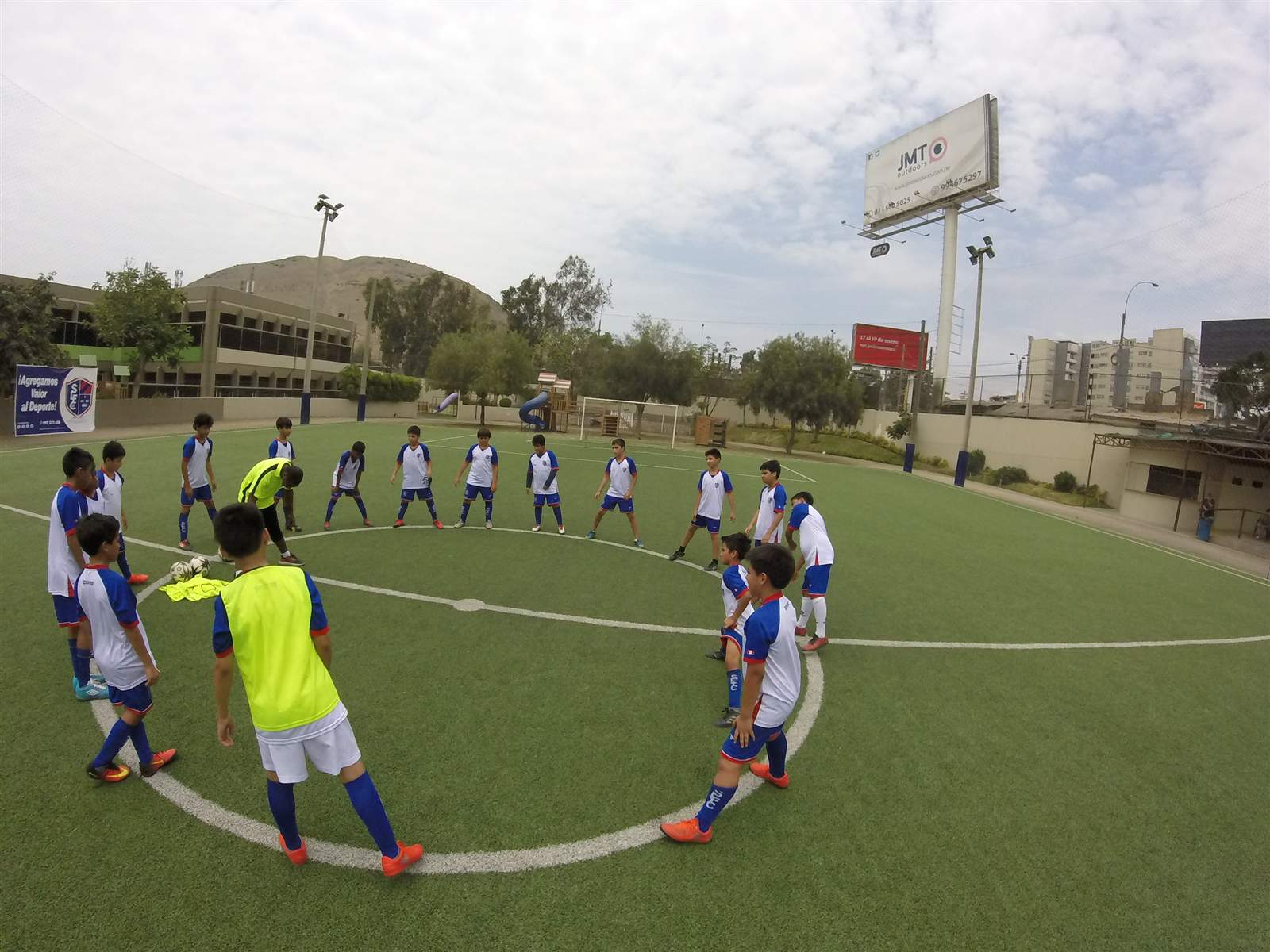 Alumnos de Soccer Lima FC en un círculo de estiramiento en la cancha, vistos desde arriba