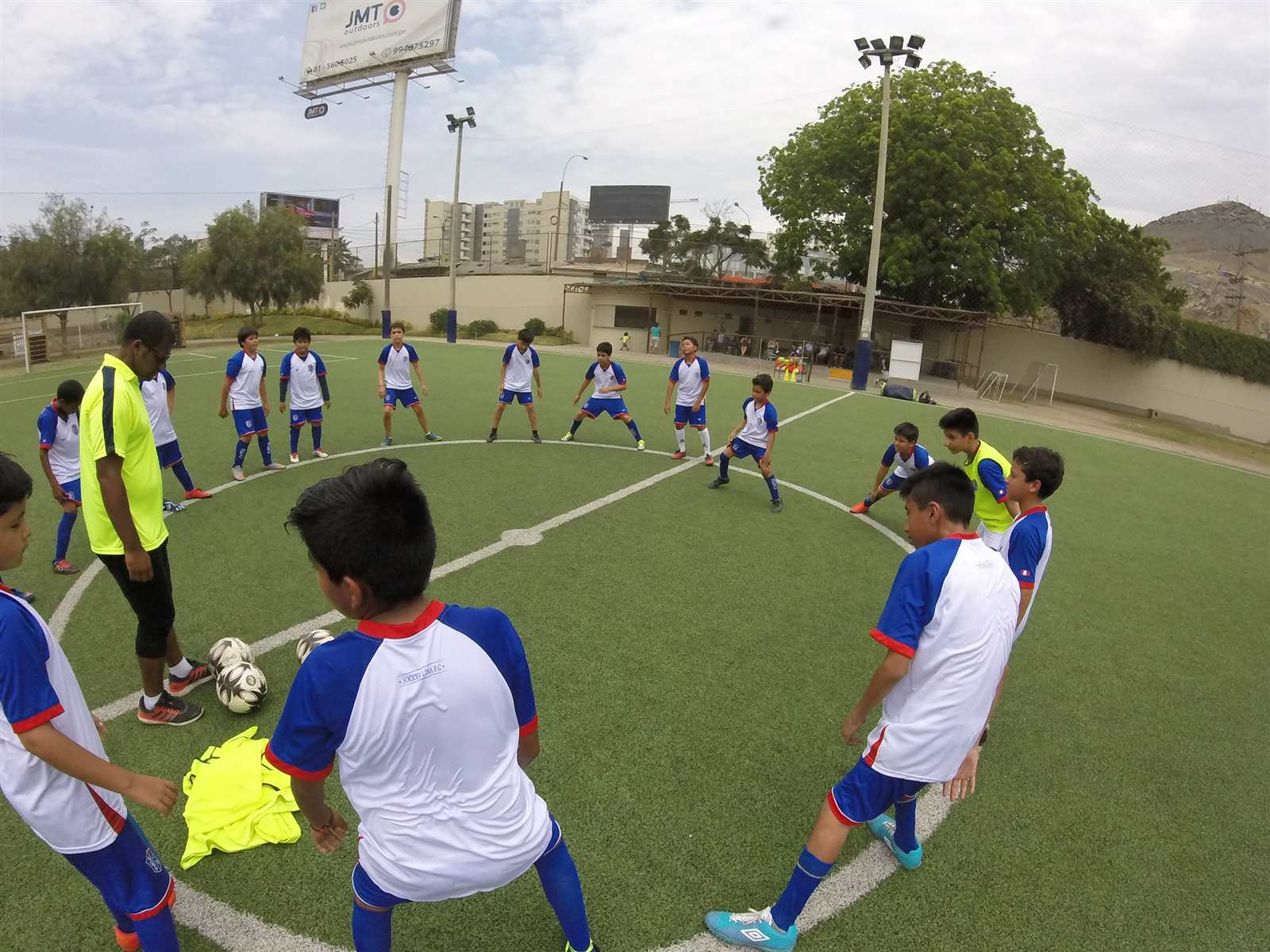 Alumnos de Soccer Lima FC en un círculo de estiramiento en la cancha, vistos desde arriba