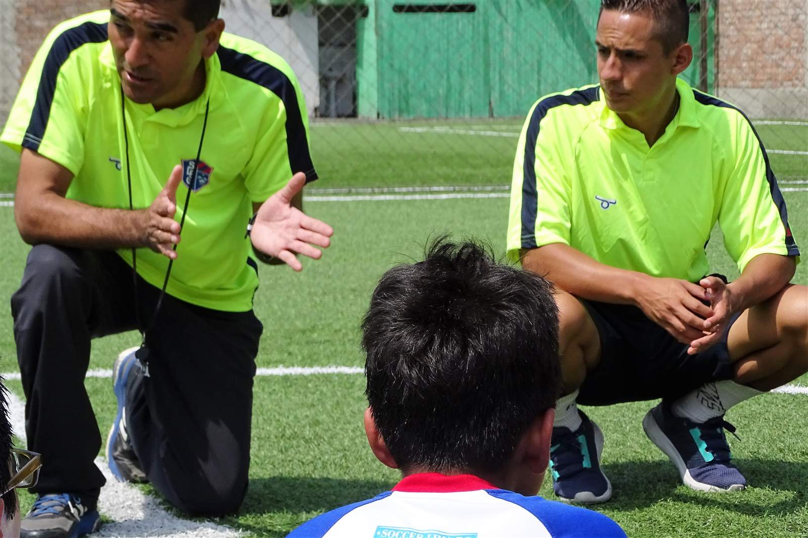 Entrenador de Soccer Lima FC hablando con un alumno agachado a su altura