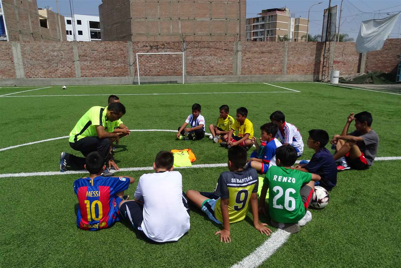 Grupo de alumnos sentados en círculo con el entrenador