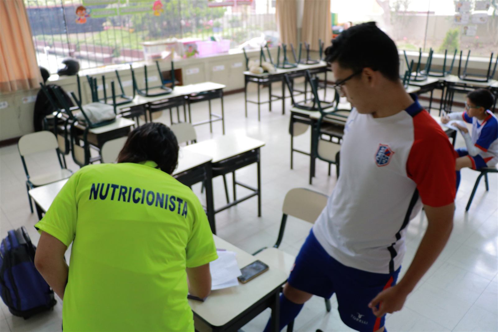 Evaluación nutricional de un alumno en un aula, con la nutricionista de Soccer Lima FC de espaldas